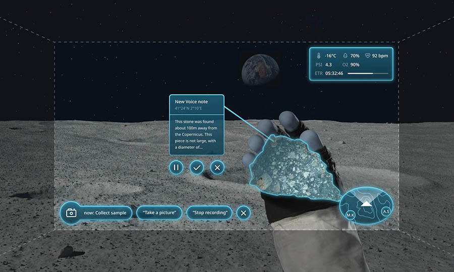 A simulated heads-up display shows a glove holding a rock on the moon's surface, with the voice commands availble to the astronaut.